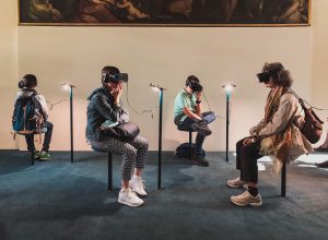 four people sitting while wearing VR headsets, exploring virtual reality
