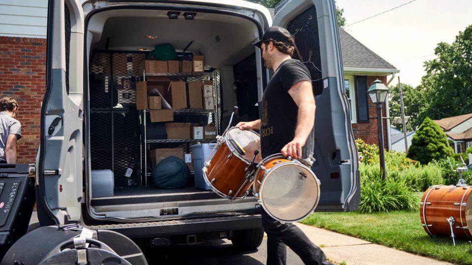 photo of a man loading drums while on tour on a shoestring budget