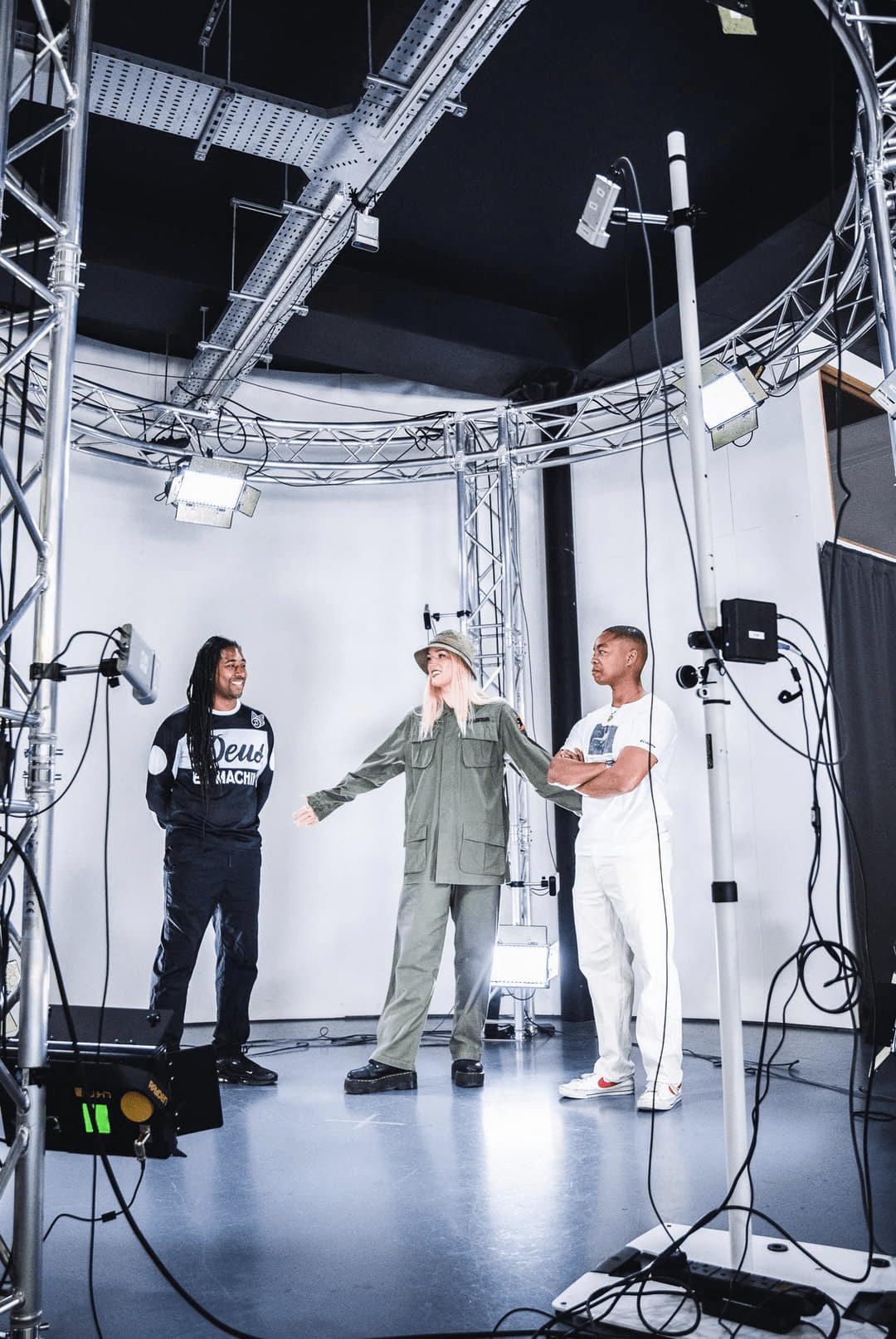 photo of two men and one woman standing and talking in a studio