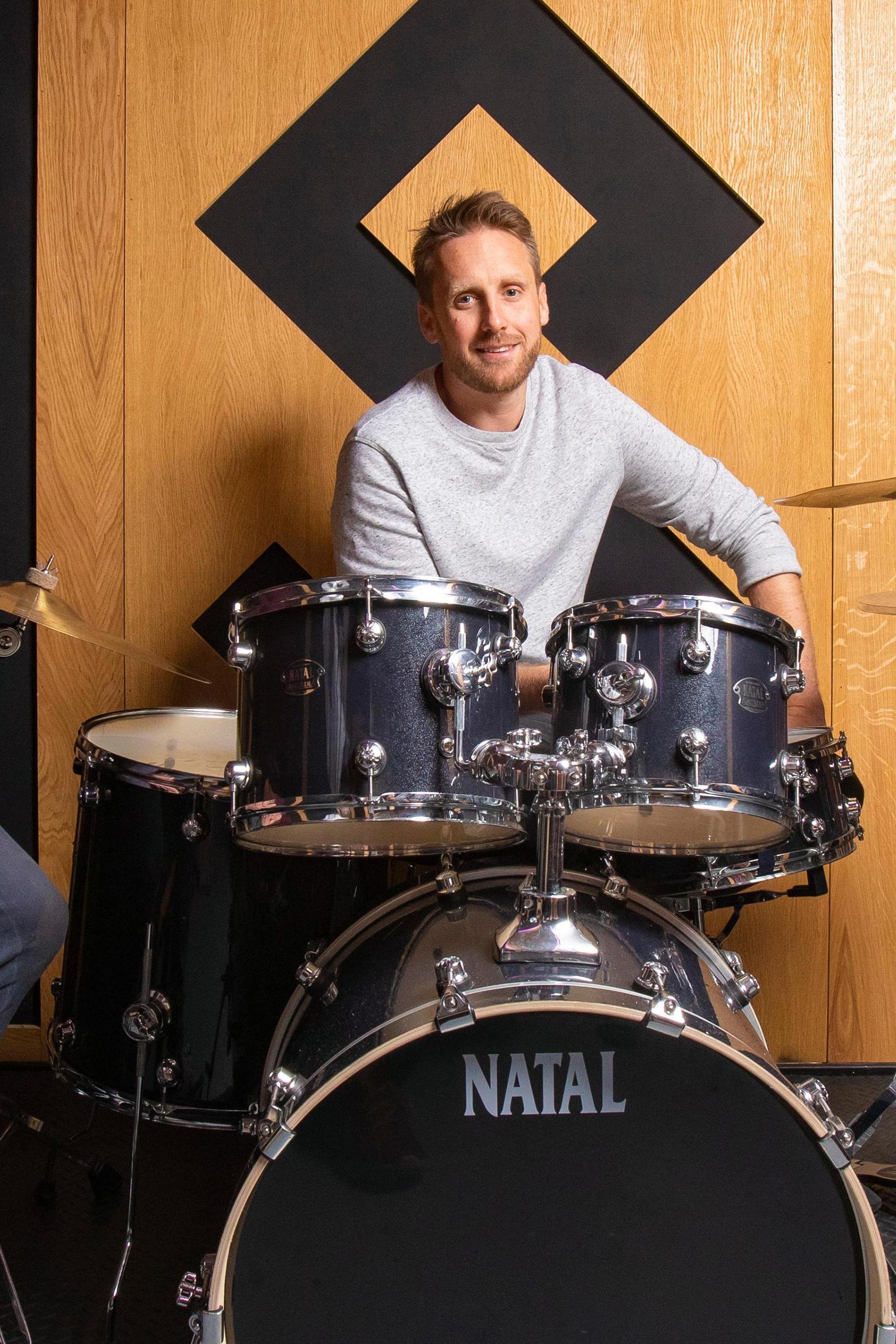 Pirate Studio's David Borrie sitting on a drum stool in front of a Natal drumkit
