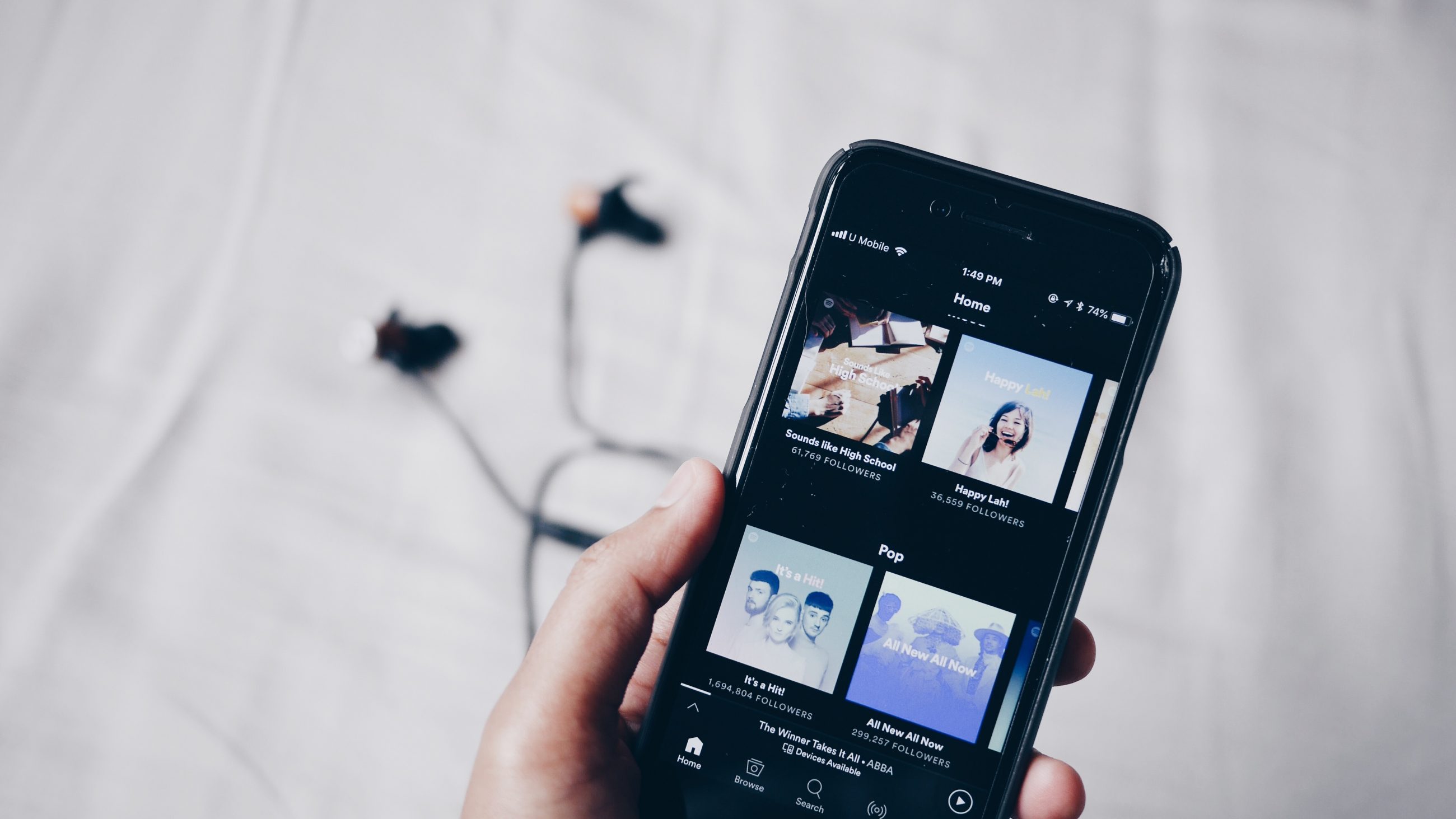 A smartphone displaying the Spotify app on its screen, showcasing the home screen with featured playlists and playlist covers.