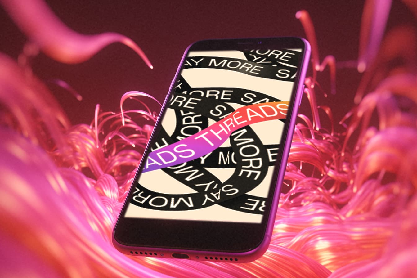 A smartphone displaying the logo of Instagram Threads, with a bright pink background.