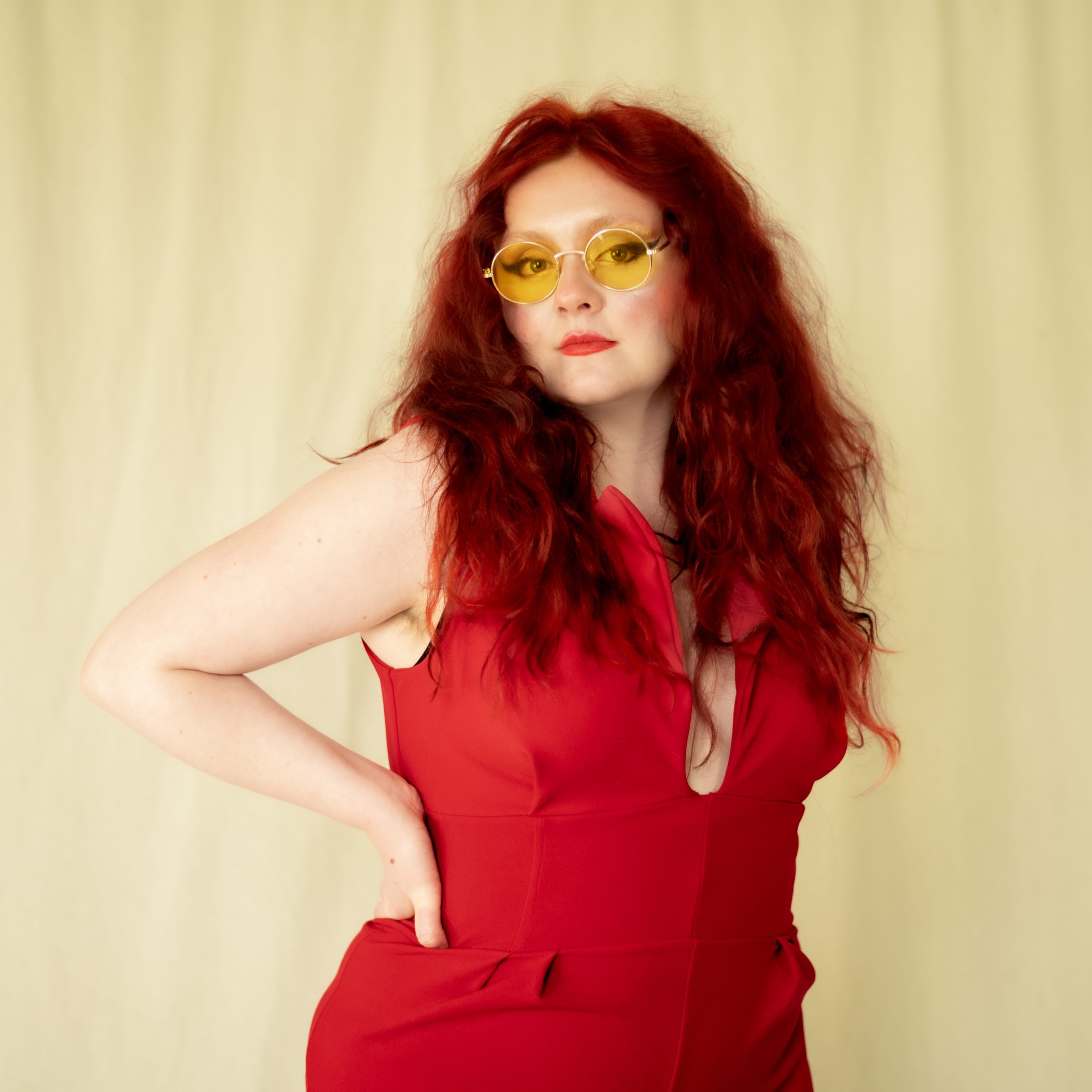 photo of artist megan black. wearing a red top and 70s-style sunglasses